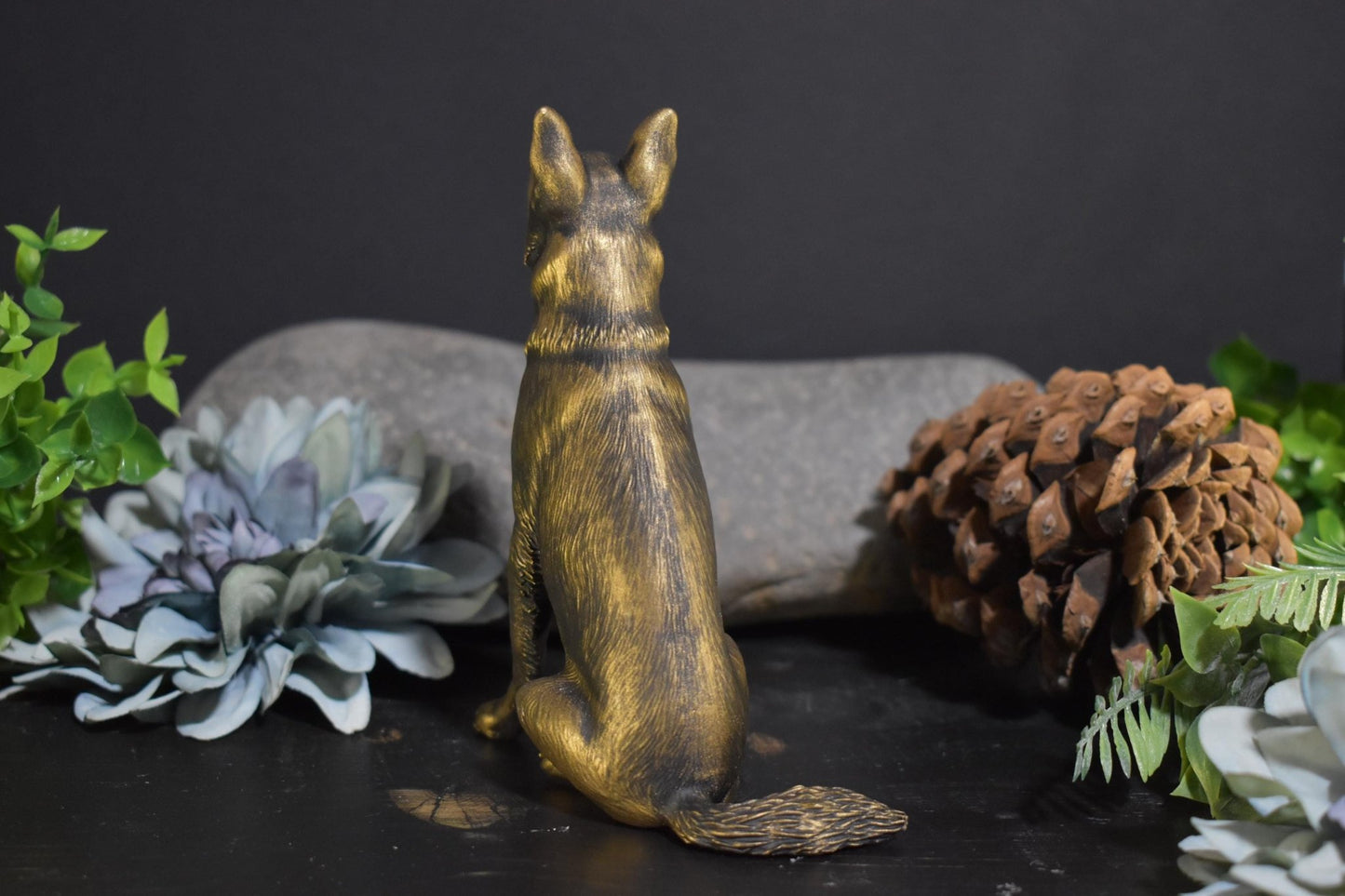 Back view of a black and gold German Shepherd sitting statue, showcasing its detailed fur texture.