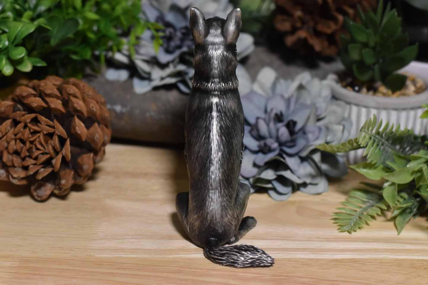 Back view of a black and silver German Shepherd sitting statue, featuring detailed fur texture.