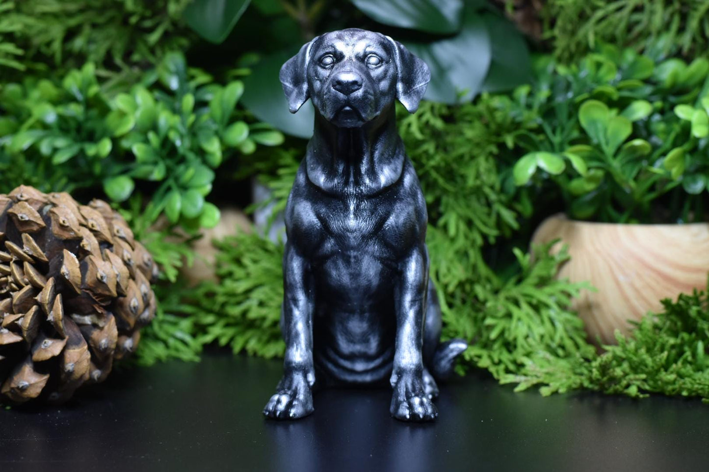 Front view of a black and silver Labrador sitting statue, highlighting its friendly and attentive look.