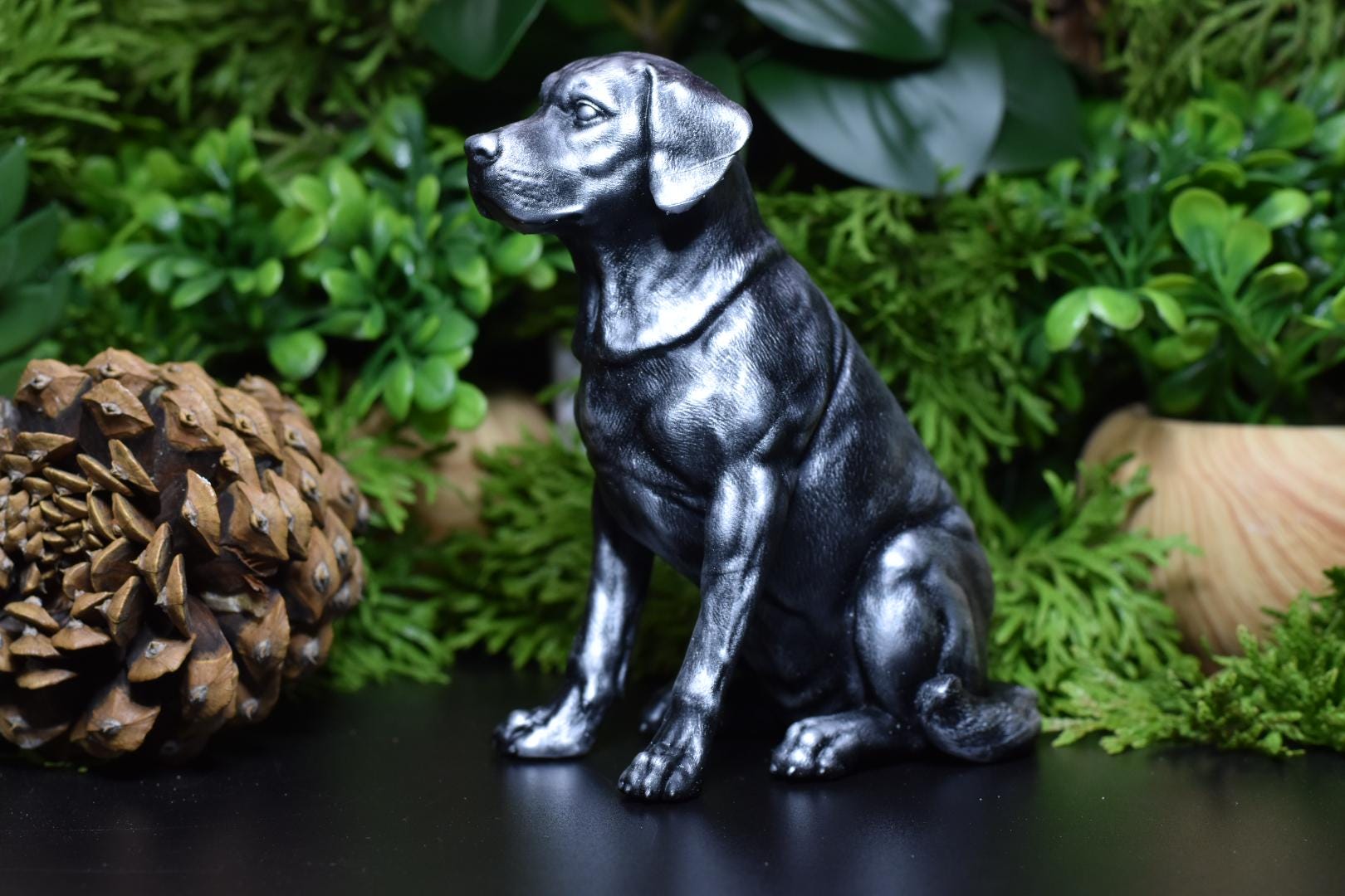 Left side view of a black and silver Labrador sitting statue, capturing its gentle and loyal expression.
